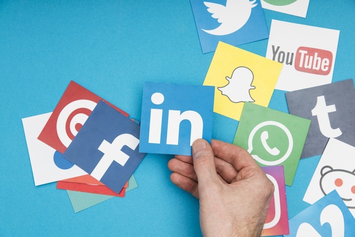 New social media features and updates to know this week. (Image: A person is holding a physical copy of the LinkedIn logo.)